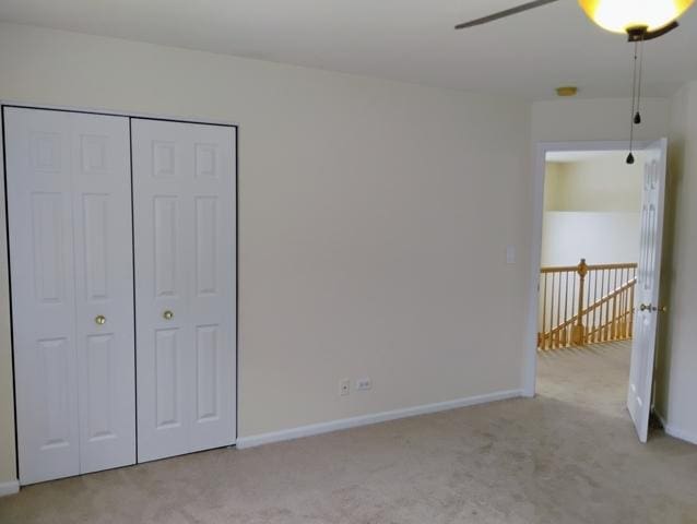 unfurnished bedroom featuring light colored carpet, ceiling fan, and a closet