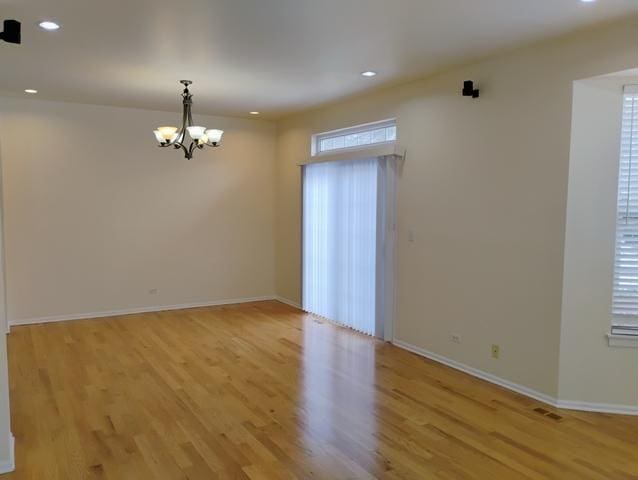 spare room featuring a notable chandelier and light hardwood / wood-style floors