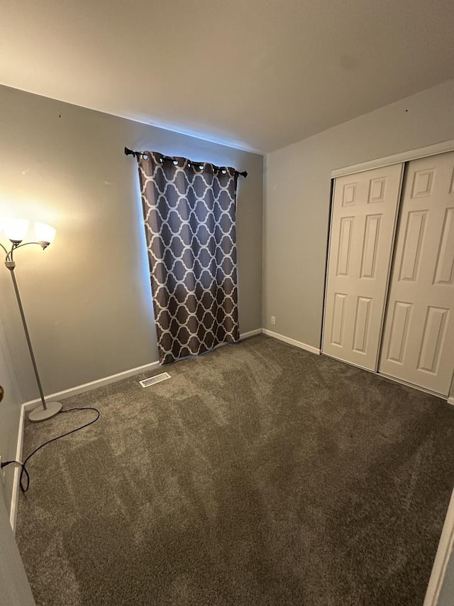 unfurnished bedroom featuring dark colored carpet and a closet