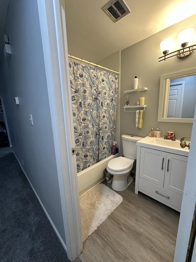 full bathroom featuring vanity, hardwood / wood-style floors, shower / bath combo, and toilet