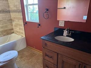 full bathroom featuring tiled shower / bath, vanity, and toilet