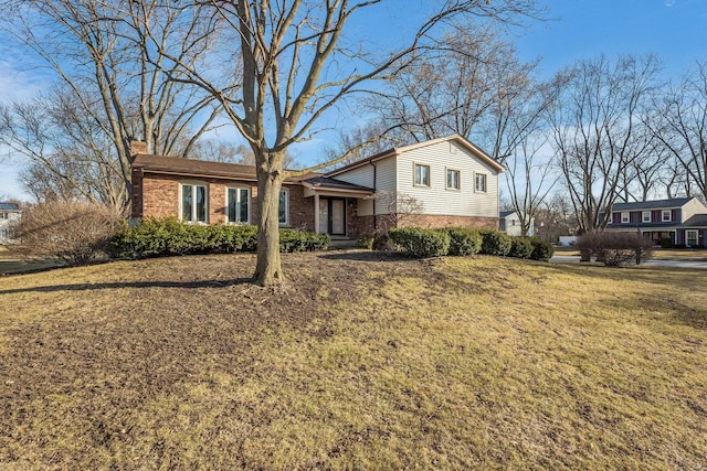 split level home with a front lawn, brick siding, and a chimney