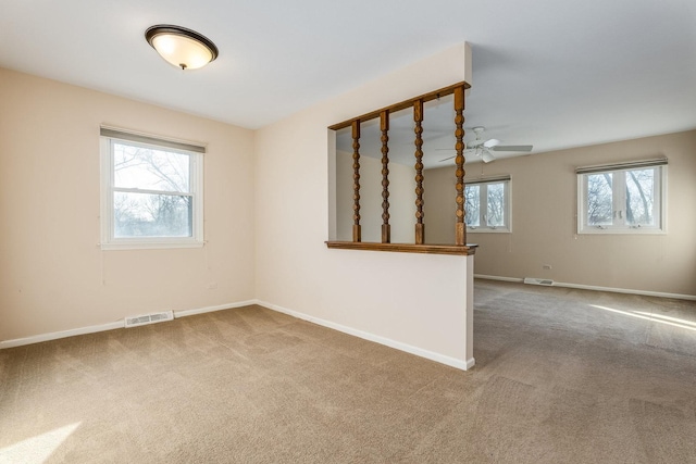 unfurnished room featuring plenty of natural light, visible vents, baseboards, and carpet floors