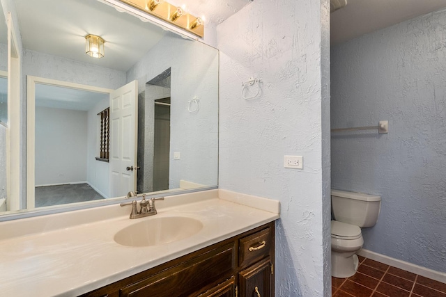 bathroom featuring baseboards, toilet, a textured wall, tile patterned floors, and vanity