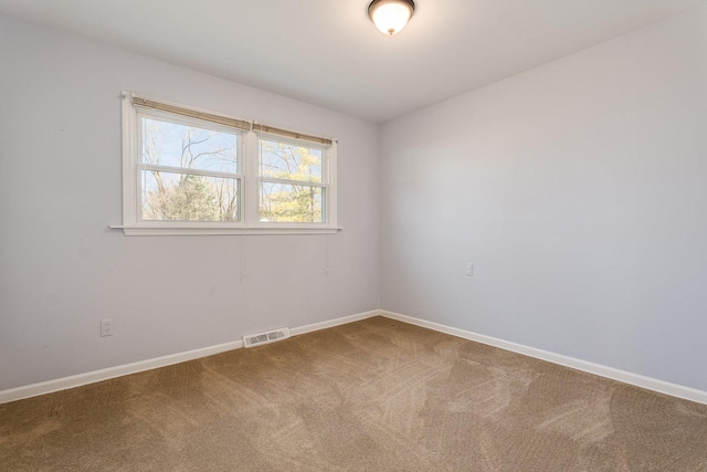 carpeted empty room featuring baseboards and visible vents