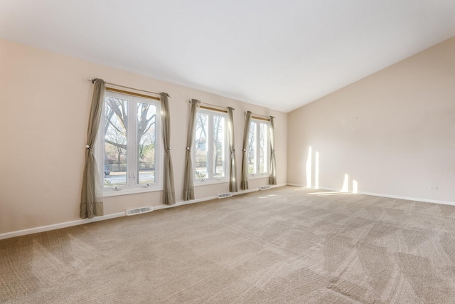 spare room with lofted ceiling, visible vents, and light carpet