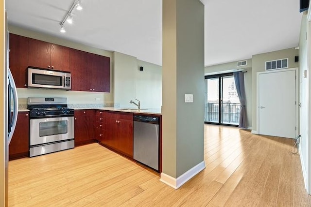 kitchen with sink, light hardwood / wood-style flooring, track lighting, and appliances with stainless steel finishes