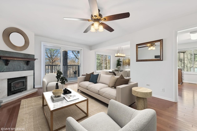 living room with a tiled fireplace, ceiling fan with notable chandelier, and hardwood / wood-style floors