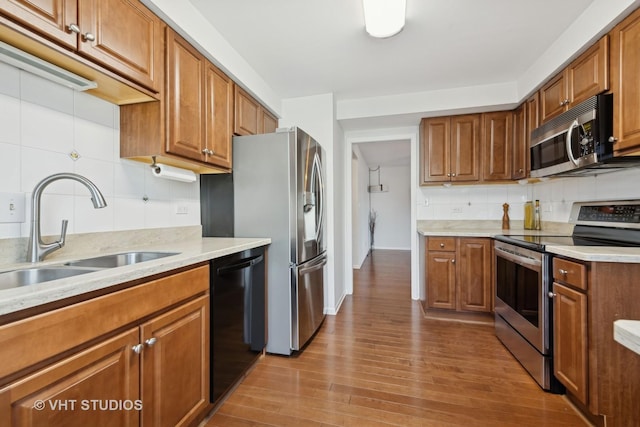 kitchen featuring sink, decorative backsplash, wood-type flooring, and stainless steel appliances