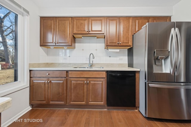 kitchen featuring dishwasher, sink, stainless steel fridge, and light wood-type flooring