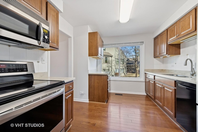 kitchen with appliances with stainless steel finishes, dark hardwood / wood-style flooring, sink, and decorative backsplash