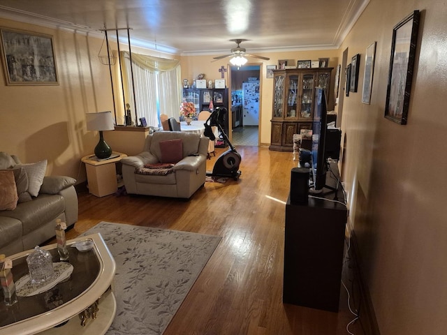 living room with wood-type flooring, ornamental molding, and ceiling fan