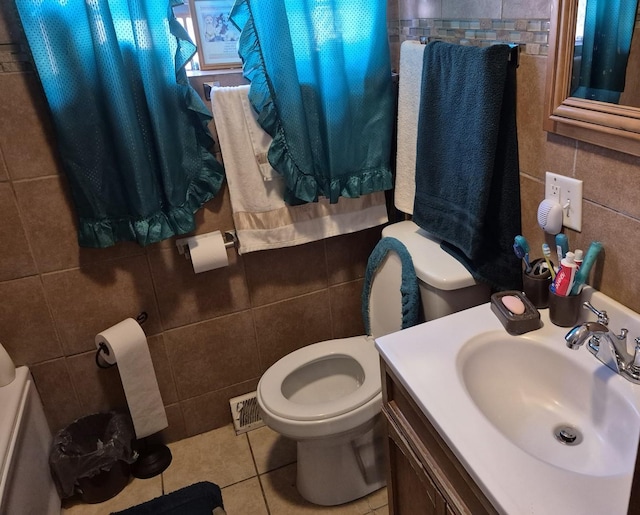 bathroom featuring tile patterned floors, vanity, toilet, and tile walls