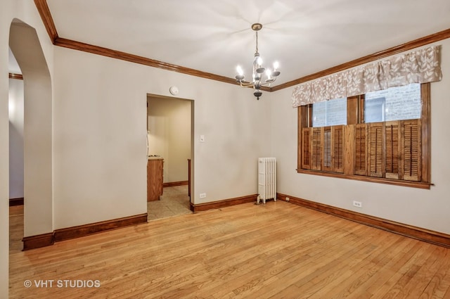 empty room with an inviting chandelier, crown molding, radiator heating unit, and light wood-type flooring