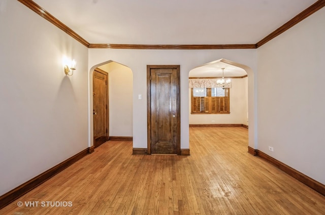 empty room featuring crown molding, light hardwood / wood-style floors, and a notable chandelier