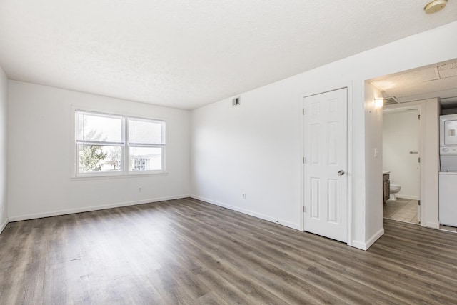 spare room featuring visible vents, a textured ceiling, baseboards, and wood finished floors