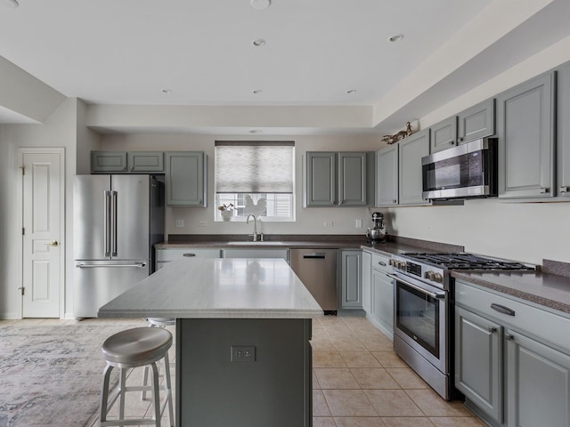 kitchen with sink, a center island, light tile patterned floors, gray cabinets, and stainless steel appliances