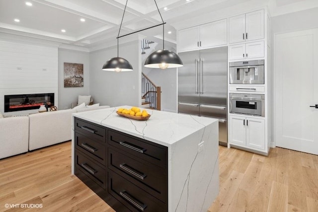 kitchen with white cabinetry, decorative light fixtures, a center island, and built in fridge