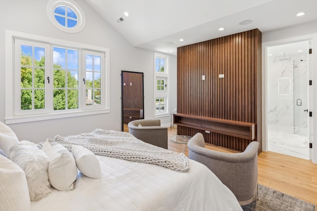 bedroom featuring wood-type flooring, ensuite bathroom, and vaulted ceiling