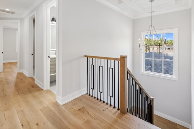 hall with beamed ceiling, coffered ceiling, a chandelier, and light hardwood / wood-style floors