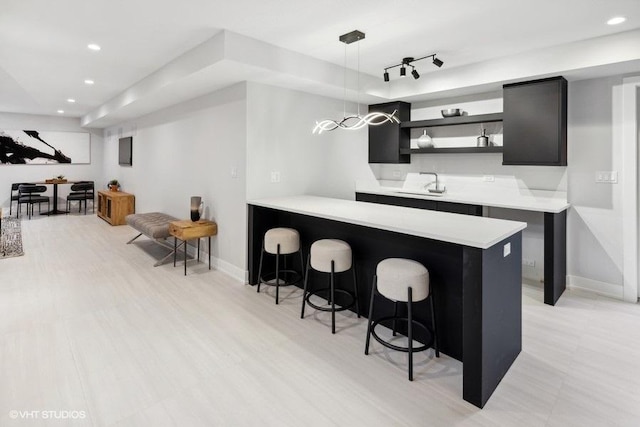 kitchen featuring a breakfast bar, decorative light fixtures, rail lighting, sink, and kitchen peninsula