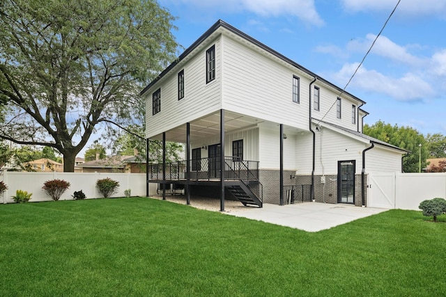 back of house with a deck, a patio area, and a lawn