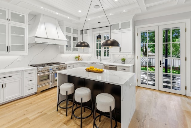 kitchen with stainless steel appliances, a center island, custom exhaust hood, and white cabinets