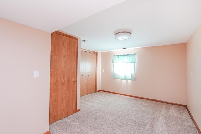 unfurnished bedroom with light colored carpet and a closet