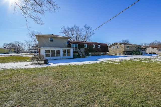 rear view of property featuring a yard and a sunroom