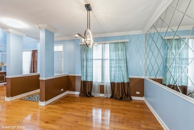 dining room featuring a notable chandelier, crown molding, baseboards, and wood finished floors