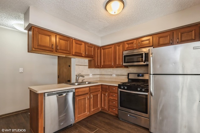 kitchen featuring stainless steel appliances, sink, a textured ceiling, and dark hardwood / wood-style floors