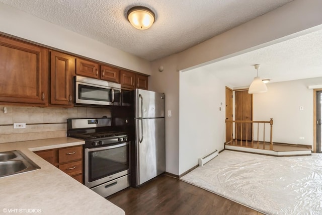 kitchen featuring appliances with stainless steel finishes, hanging light fixtures, a textured ceiling, dark hardwood / wood-style flooring, and a baseboard radiator