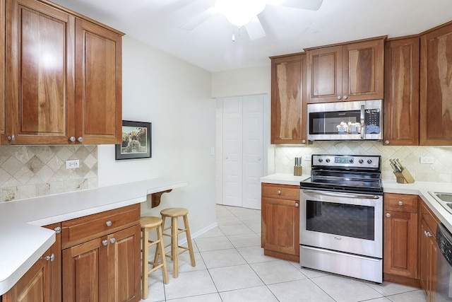 kitchen with backsplash, stainless steel appliances, ceiling fan, and light tile patterned flooring