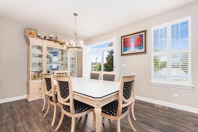 dining space with a notable chandelier, dark wood-type flooring, and a healthy amount of sunlight