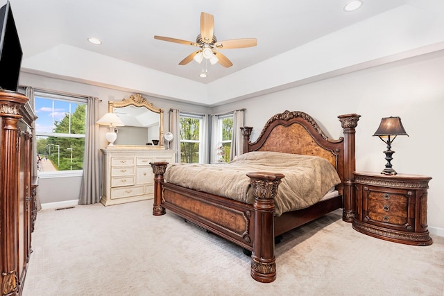 carpeted bedroom featuring ceiling fan and a tray ceiling