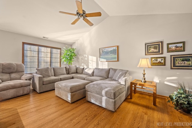 living room with ceiling fan, vaulted ceiling, and light wood-type flooring