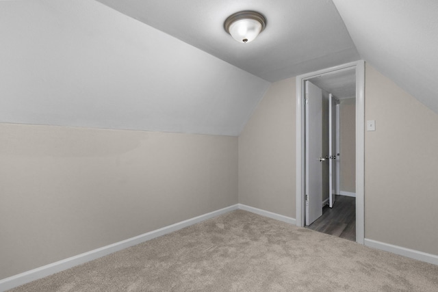 bonus room with lofted ceiling and dark carpet