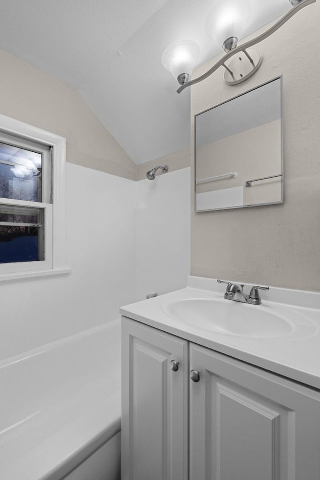 bathroom with vaulted ceiling, bathing tub / shower combination, and vanity