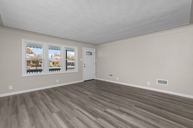 spare room featuring dark hardwood / wood-style flooring and a textured ceiling