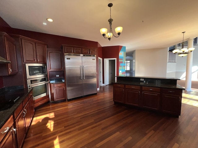 kitchen with decorative light fixtures, built in appliances, dark hardwood / wood-style flooring, and a notable chandelier