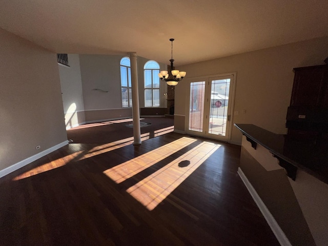 unfurnished dining area with dark wood-type flooring, decorative columns, and a chandelier