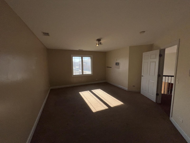 unfurnished room featuring dark carpet