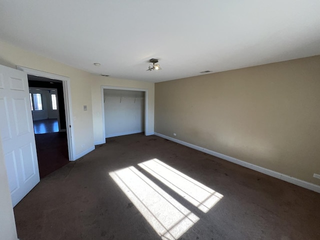 unfurnished bedroom featuring dark carpet and a closet