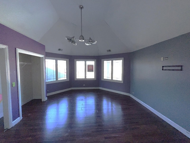 interior space featuring dark wood-type flooring, vaulted ceiling, and multiple windows