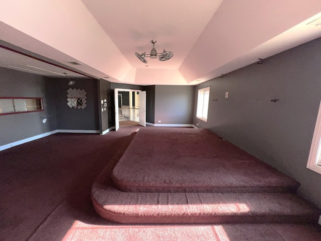 interior space featuring a tray ceiling, ceiling fan, and carpet flooring