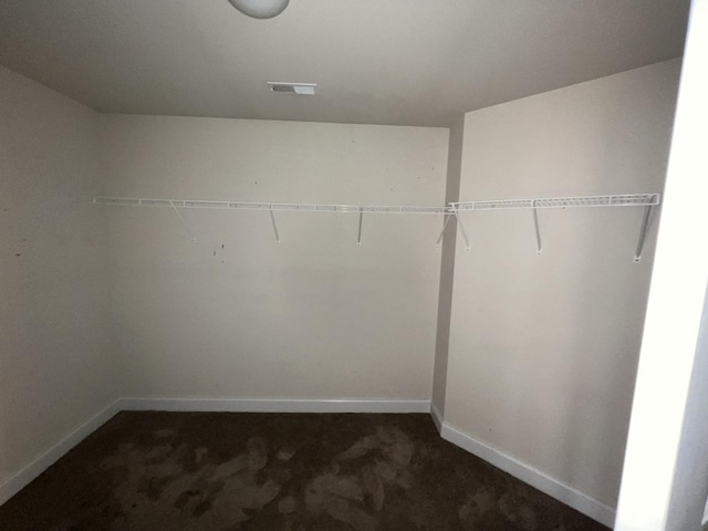 walk in closet featuring dark carpet