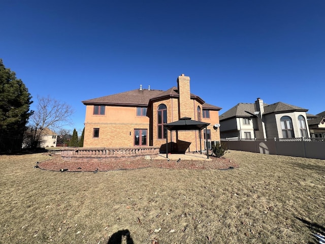 rear view of property featuring a gazebo, a patio area, and a lawn