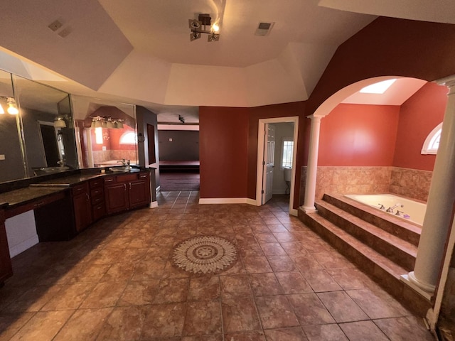 bathroom with a relaxing tiled tub, vanity, and ornate columns