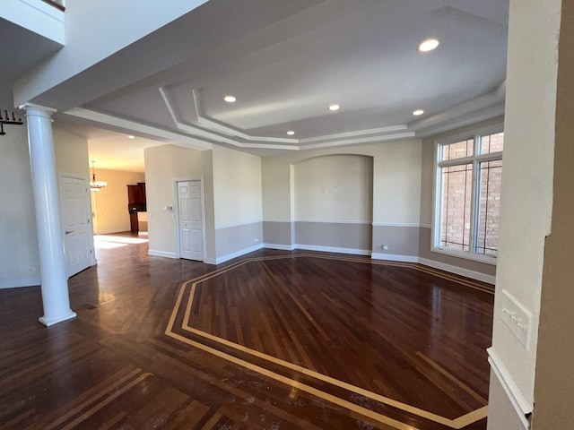 empty room featuring decorative columns and a tray ceiling