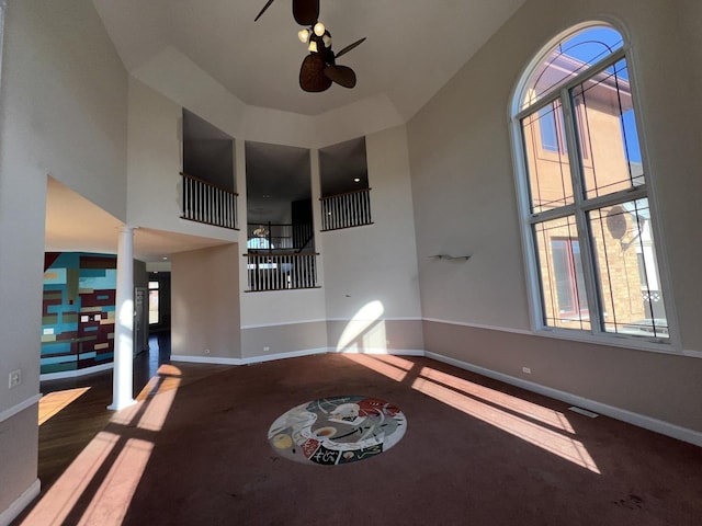 unfurnished living room with decorative columns, a high ceiling, and ceiling fan